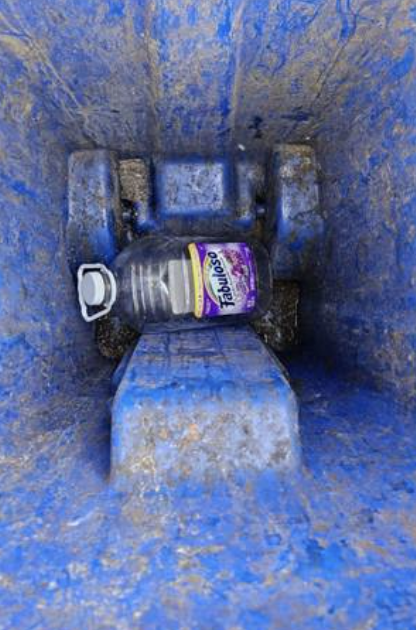 Close-up of residue inside a dirty blue bin before washing